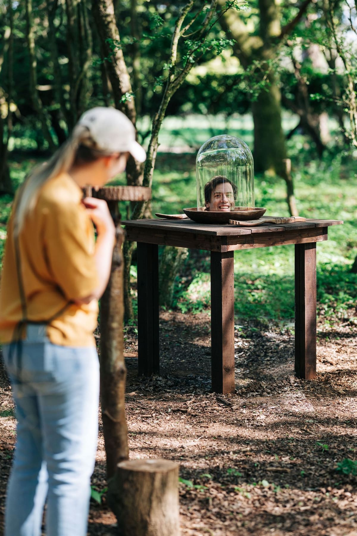 A guest pauses on the woodland illusion trail before a smiling head apparently served on a plate beneath a glass dome